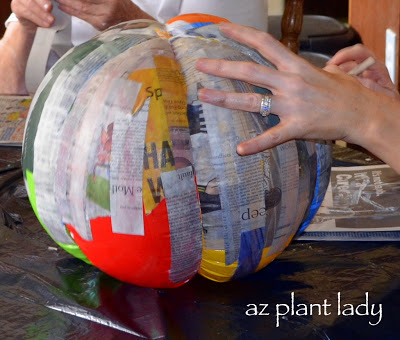 placing paper mache strips on beach balls