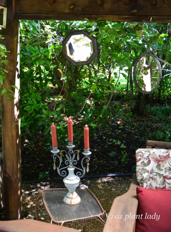 A candelabra graces a side table underneath the shade of the gazebo while mirrors reflect other areas of the garden.  Southwest garden style
